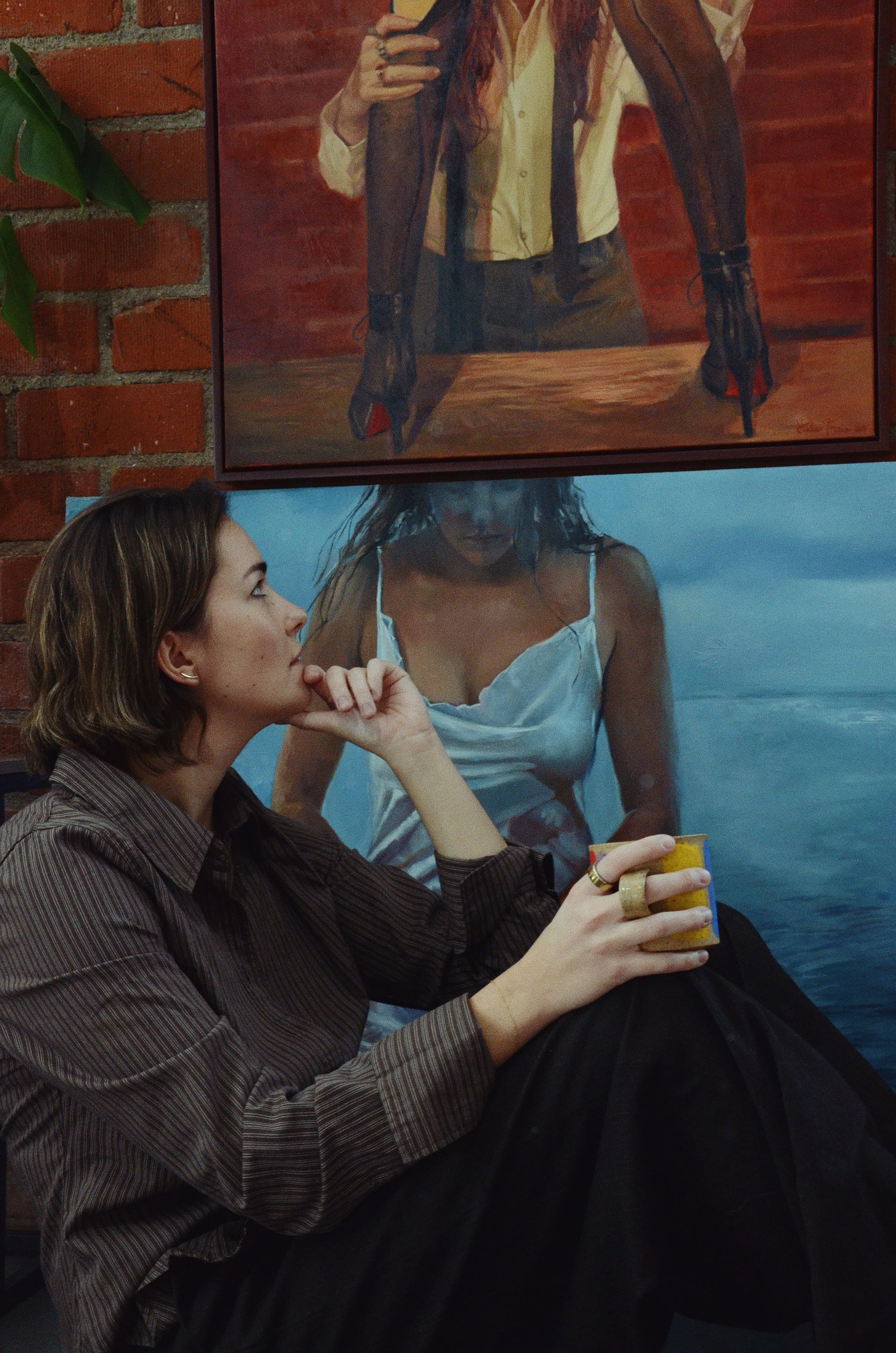 woman with coffee sitting in front of painting