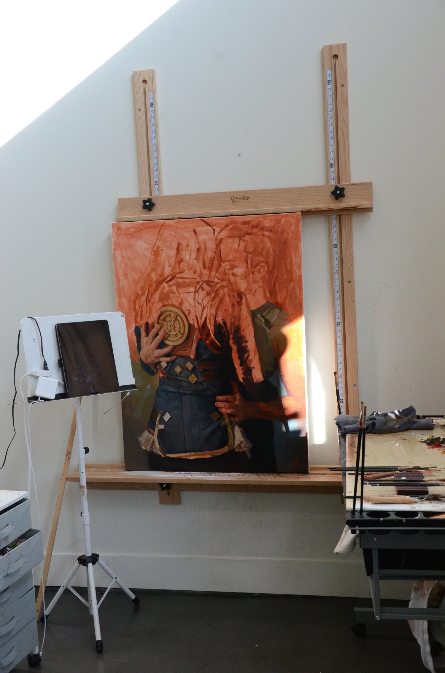 Artistic setup with a canvas on an easel, light source, and camera equipment.