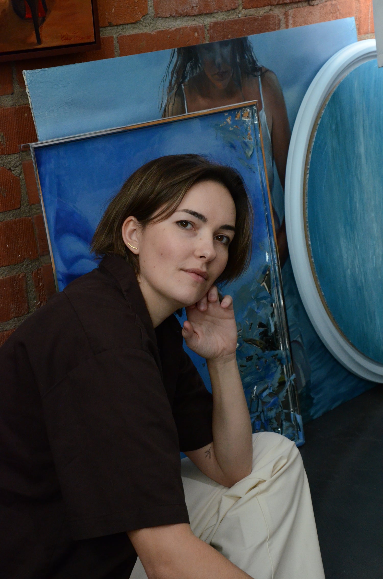 woman in front of blue paintings.