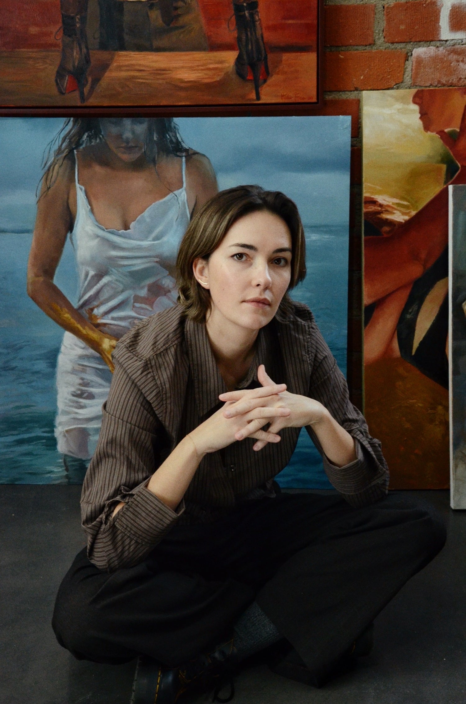 Woman sitting in front of a wall with framed artworks